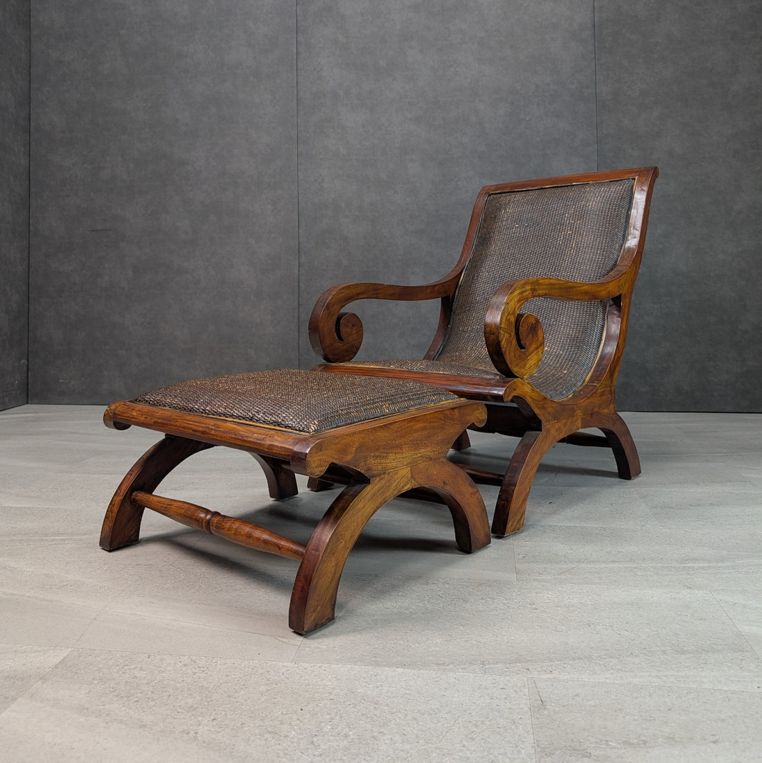 Late 20th century British Colonial Revival plantation lounge chair with matching woven cane ottoman, scroll arms and curved timber frame