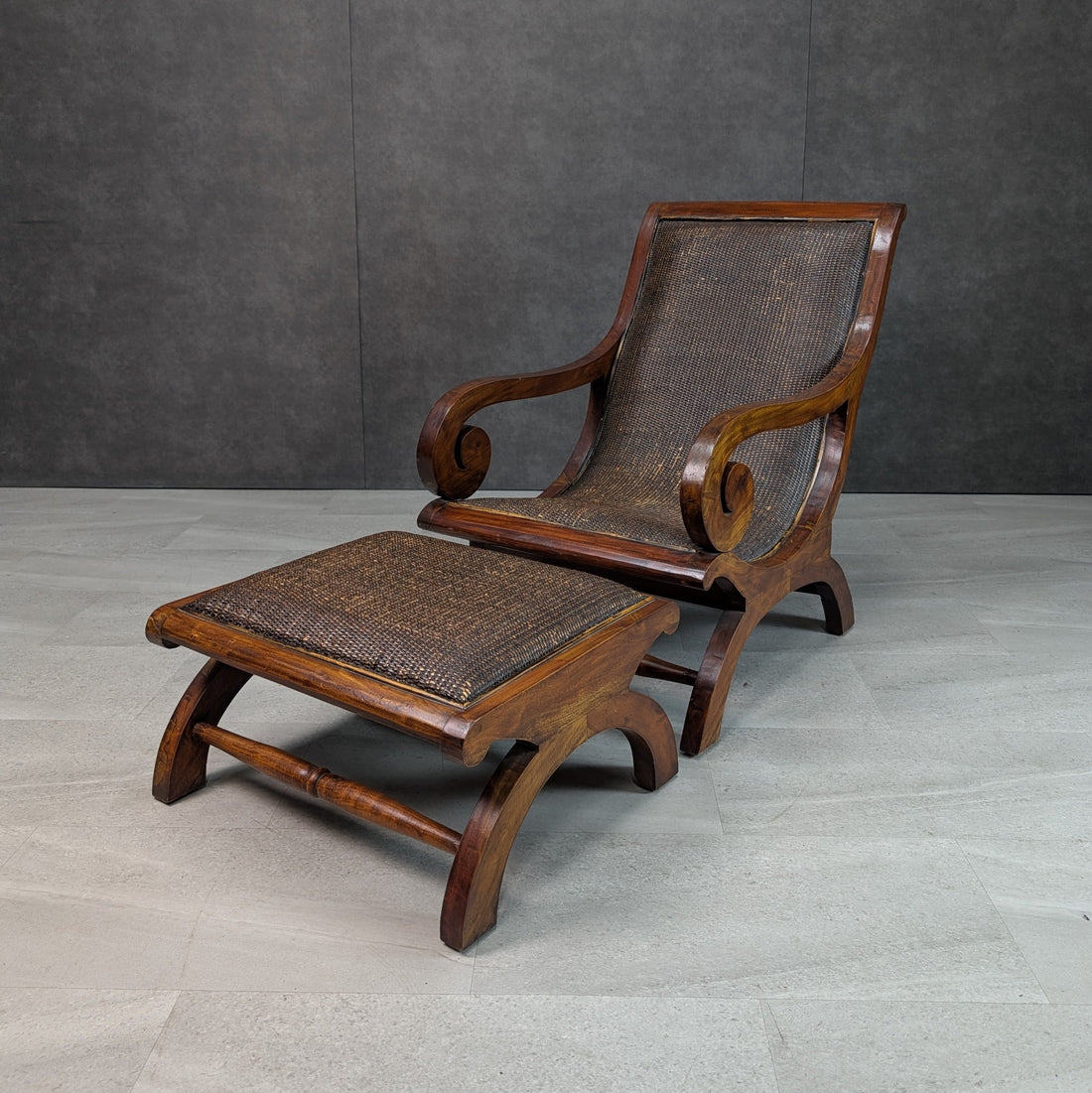 Three quarter view of British Colonial Revival timber plantation chair with dark woven cane back seat and matching ottoman