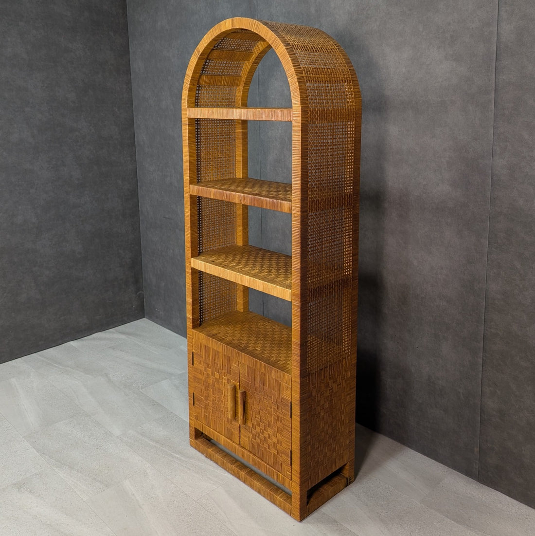Three quarter view of arched rattan bookcase showing woven sides and open shelving