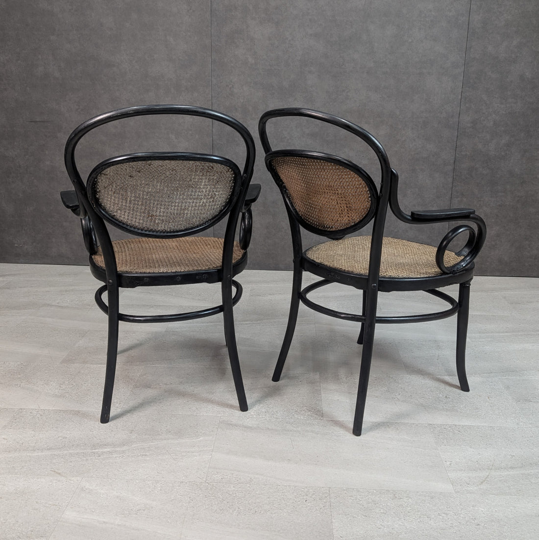 Rear view of two antique bentwood and cane armchairs with oval woven cane backrests