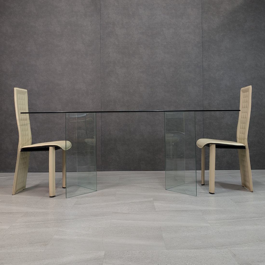 Long side view of Italian style clear glass dining table with two glass trestle bases and chairs for scale