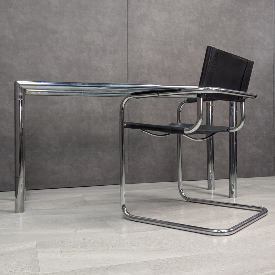 Vintage chrome glass console and black leather tubular steel cantilever chair rear perspective