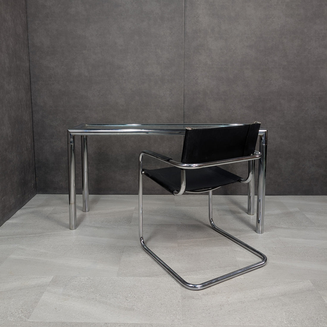 Chrome and glass console with black leather cantilever armchair arranged together