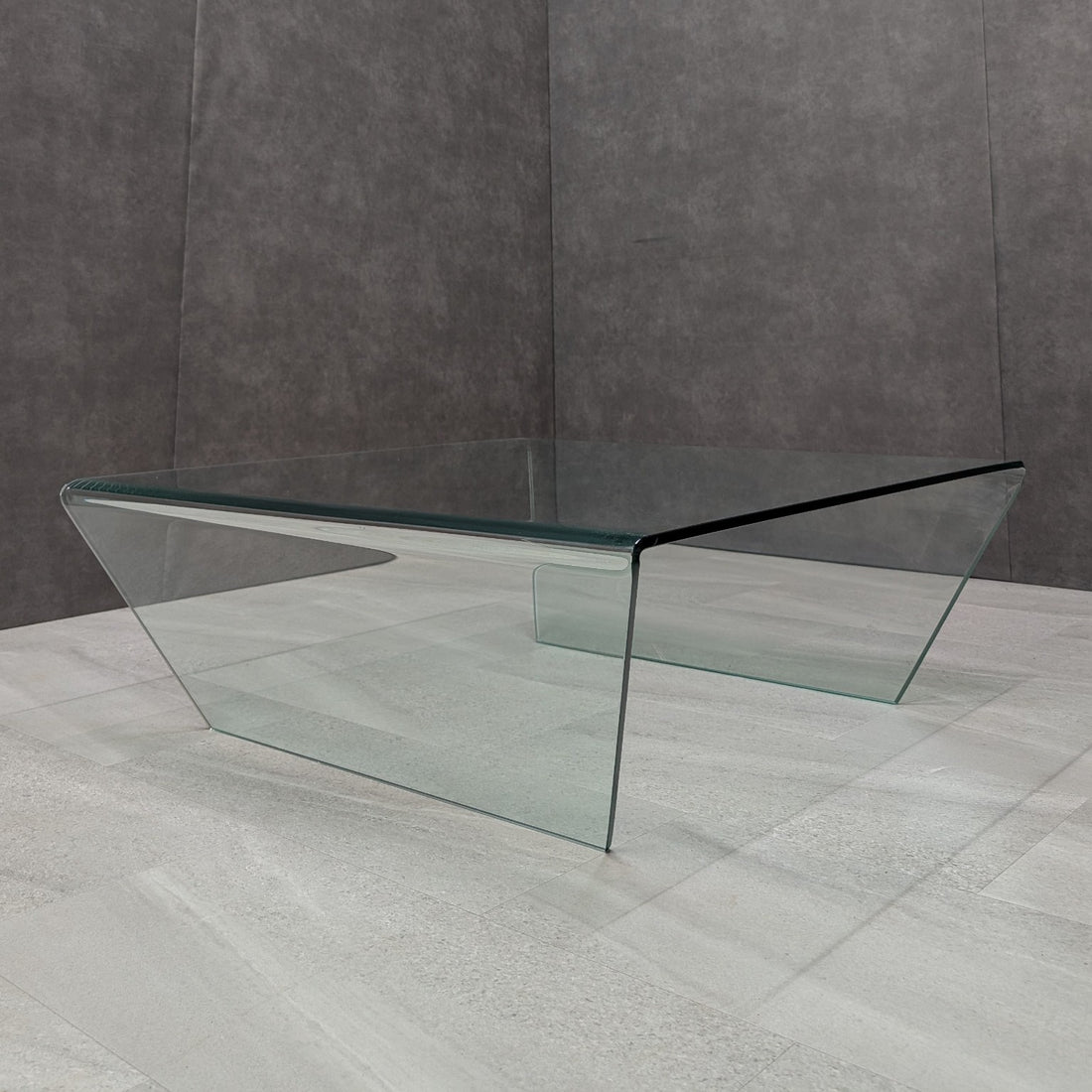 Clear bent glass coffee table with inward angled waterfall sides, three-quarter view