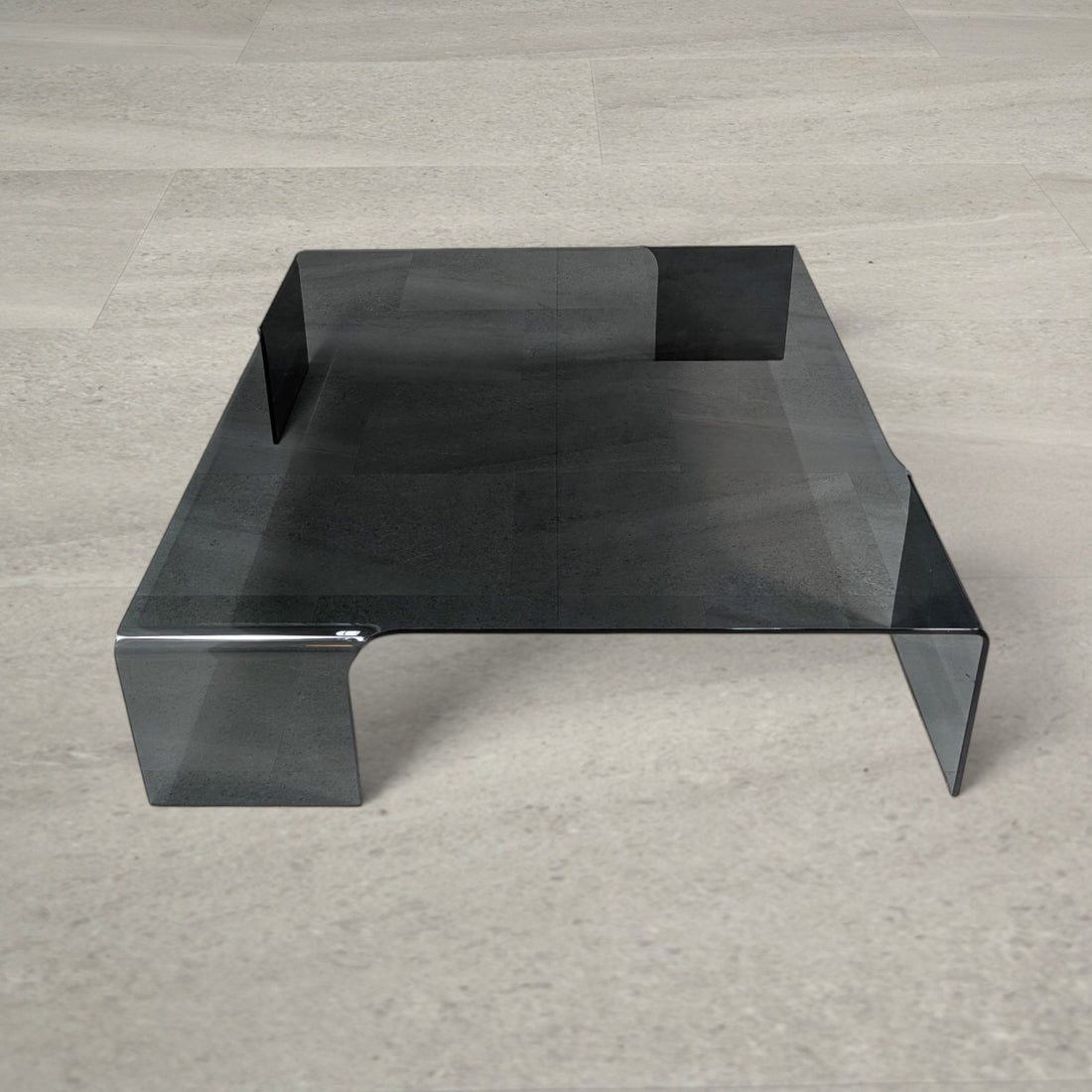 Elevated view of the 113cm square smoked grey glass coffee table and its four integrated legs