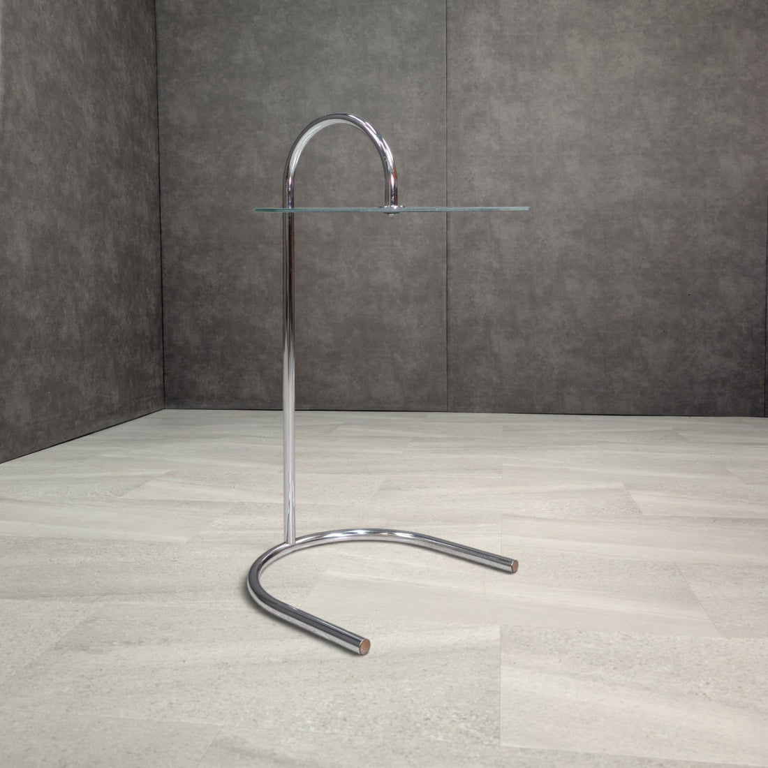 IKEA RY side table showing its circular clear glass top, chrome arch handle and open curved base