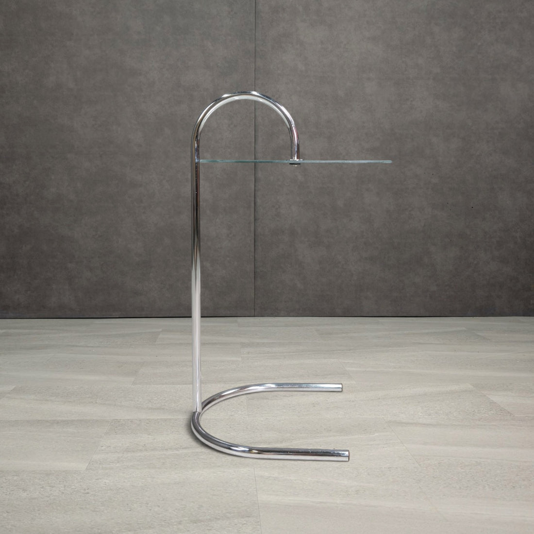 Side profile of IKEA RY chrome and glass table showing its arched handle and horseshoe base
