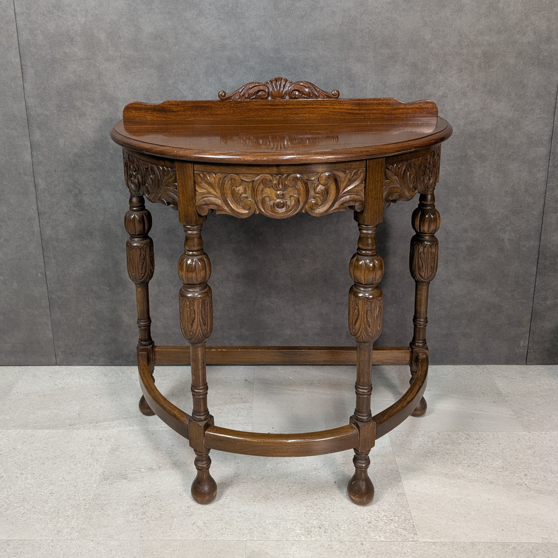 Circa 1920s Jacobean Revival carved timber demi lune hall table, three quarter view