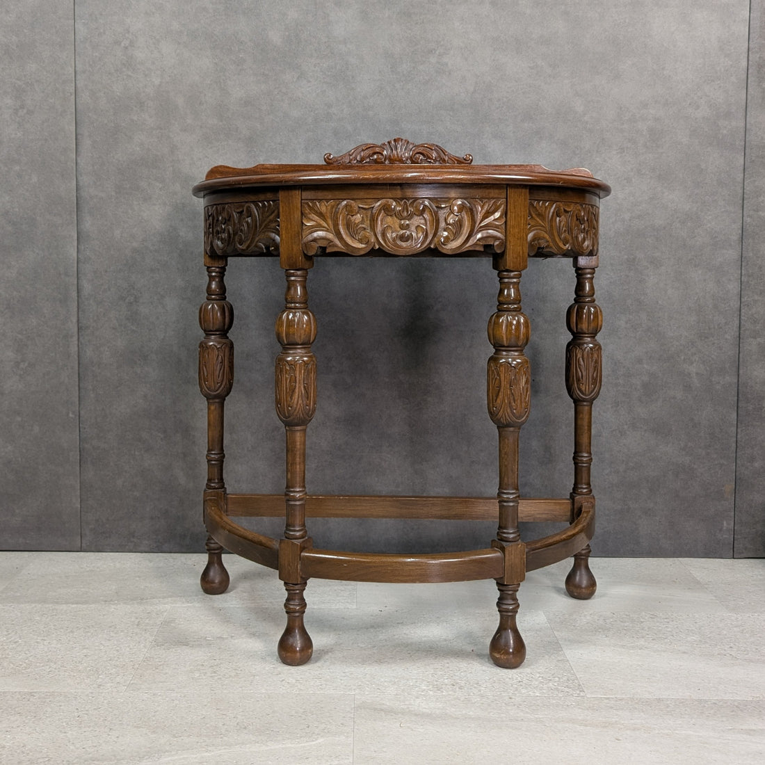 Circa 1920s Jacobean Revival carved demi lune hall table, front view