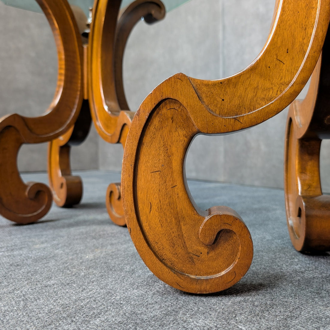 Detail of the warm timber finish, shaped scroll foot and surface marks