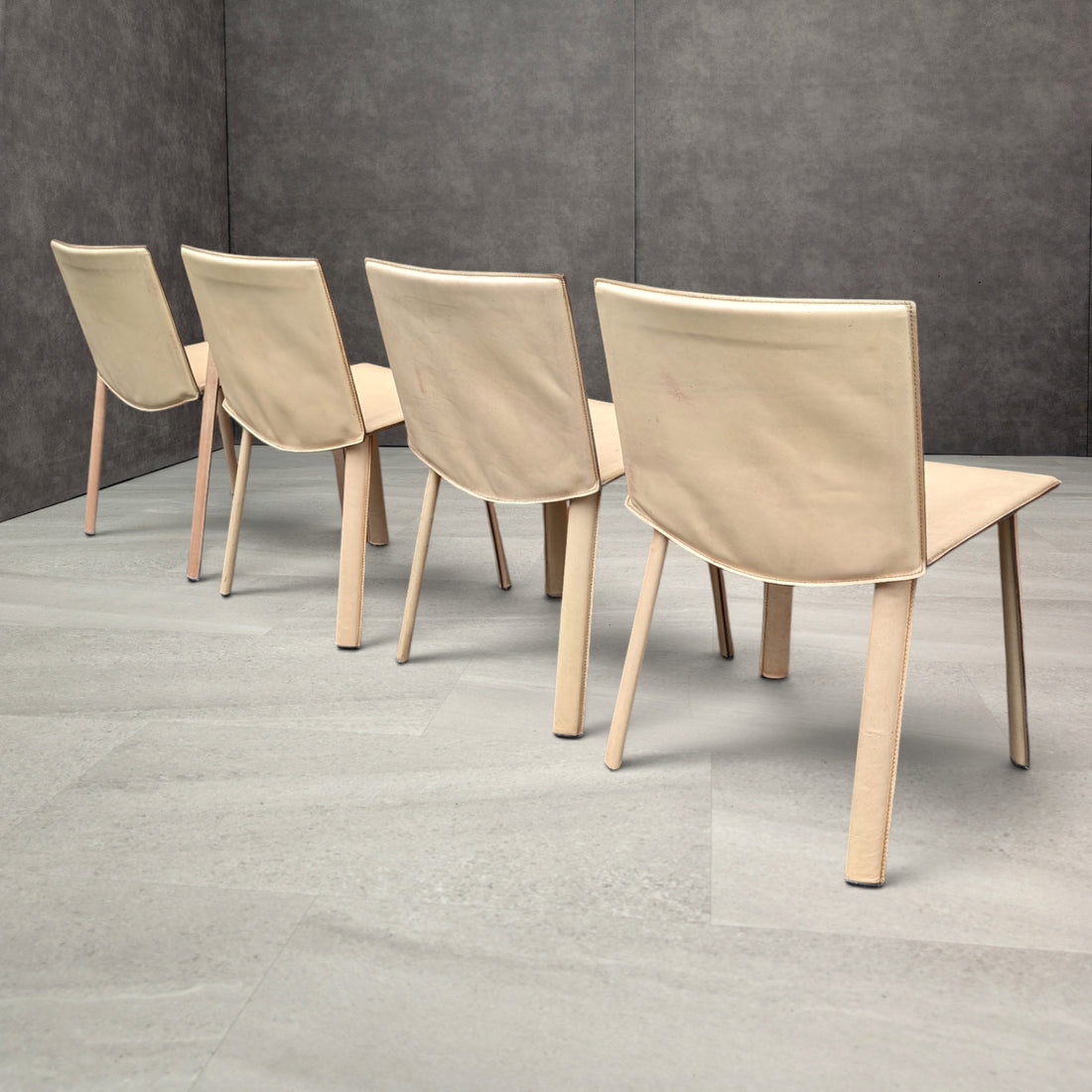 Four Poltrona Frau Ribot leather dining chairs shown from the back