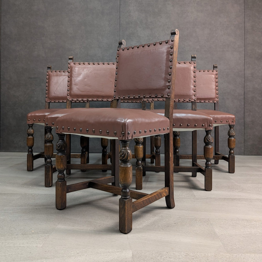 Set of six circa 1900 Jacobean Revival English oak dining chairs with recently renewed brown leather upholstery, three quarter view