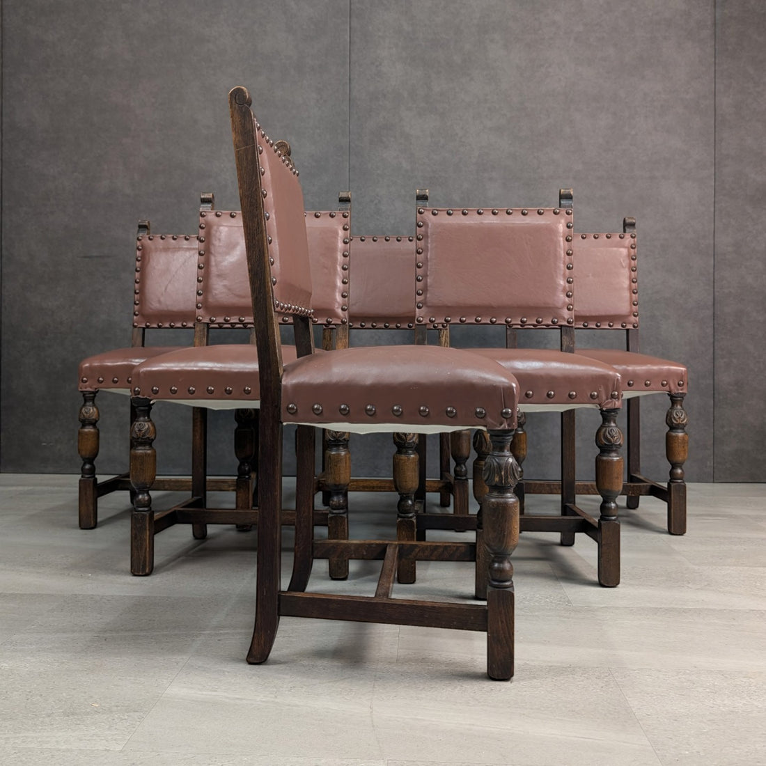 Side profile of an English oak dining chair showing leather upholstery, carved front legs and stretcher frame
