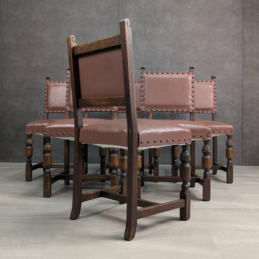 Rear view of a Jacobean Revival oak dining chair showing the oak back frame, rear legs and stretchers