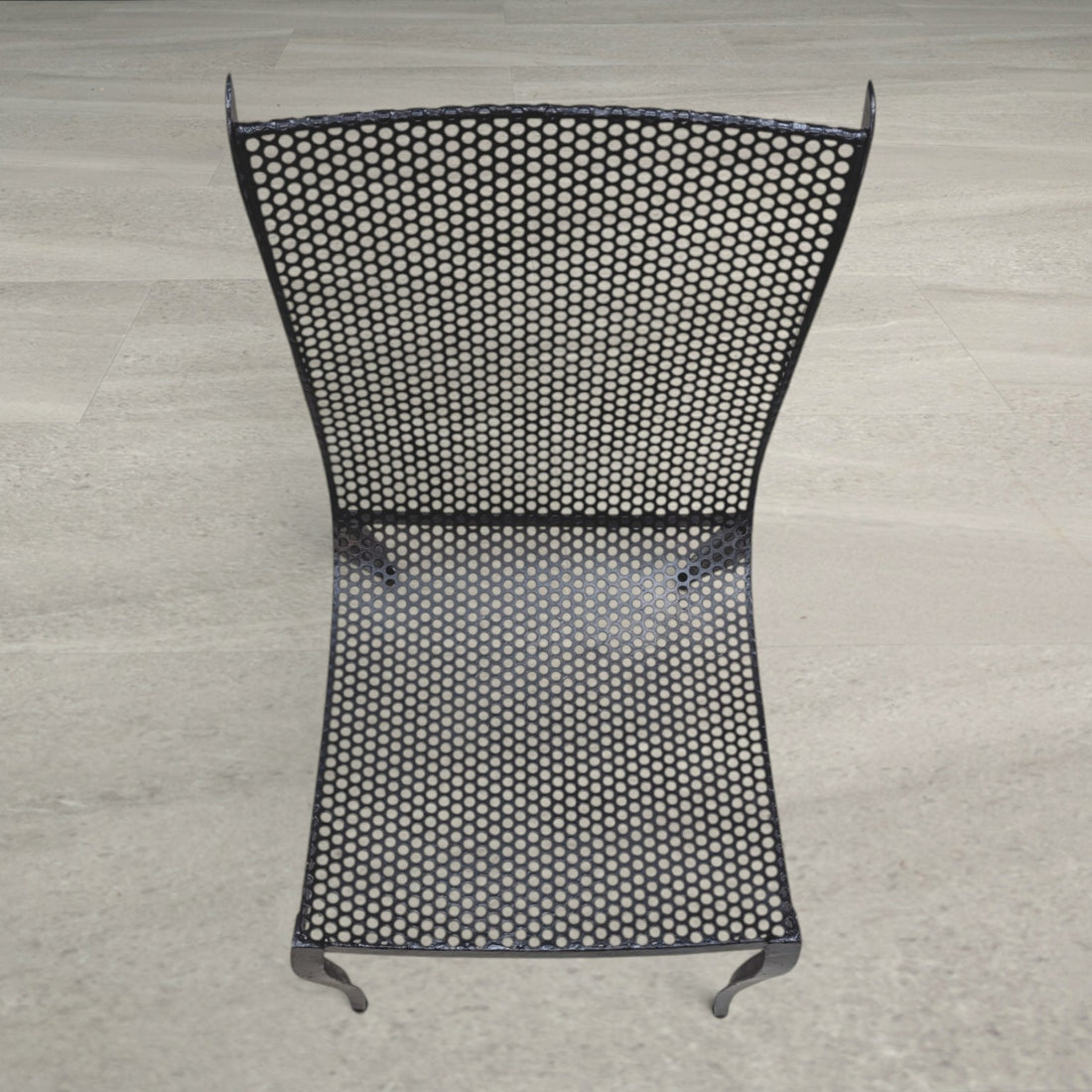 Overhead detail of the perforated aluminium seat and back with visible wear to the black finish