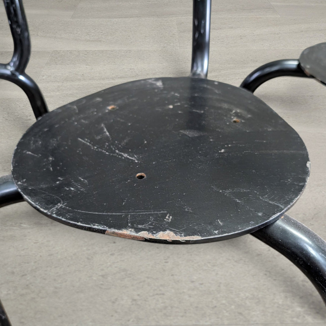Close-up of steel seat plate showing fixing holes, chipped paint and surface wear
