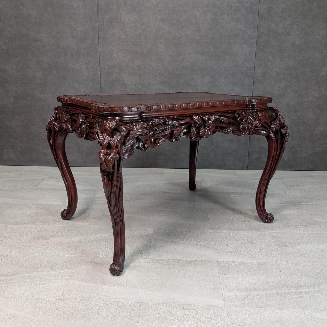 Close detail of deep carved floral foliage and curved cabriole leg on a Meiji export table