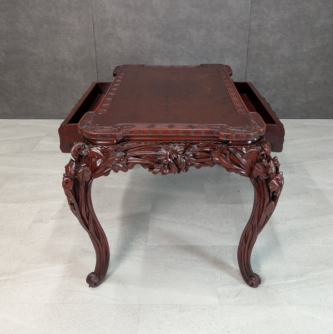 Front elevation of Japanese carved hardwood writing table with floral relief apron and scroll feet