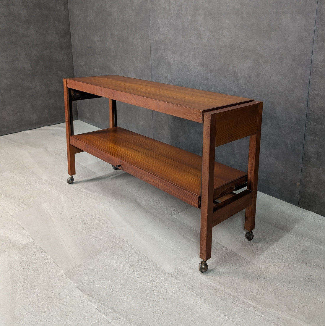 Vintage mid century teak convertible console table folded to slim two tier configuration on castors