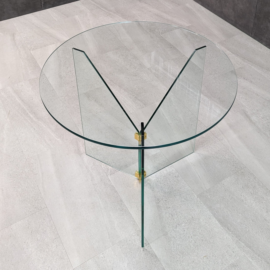 Elevated angle revealing circular glass top and triangular cutaways of the clear glass base