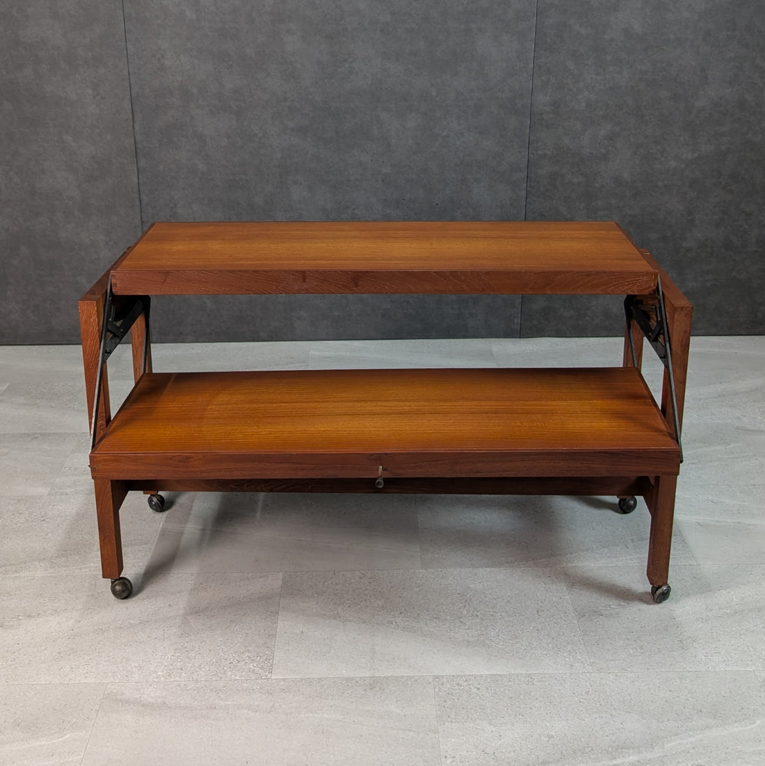 Front view of teak two tier console and serving trolley with rectangular timber shelves and castors